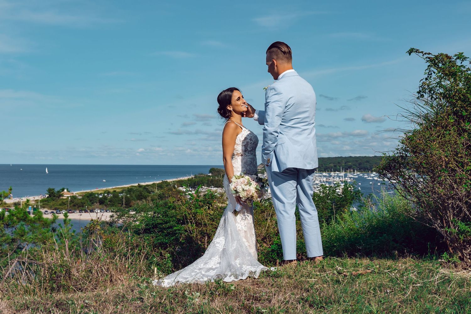 Couple sharing a wedding moment on a cliff overlooking a harbor.