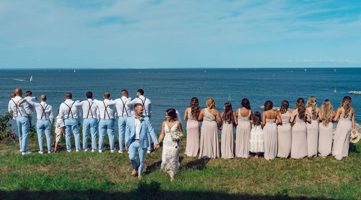 Wedding party photographed together on a coastal hilltop.